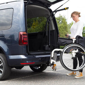Une femme rentre un fauteuil roulant à l'intérieur de son véhicule grâce à un aménagement de grue de coffre