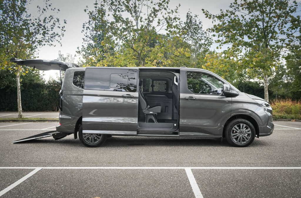 Ford Tourneo Custom TPMR avec sa porte coulissante latérale ouverte, son hayon et sa rampe déployée - Véhicule TPMR - Transport handicap