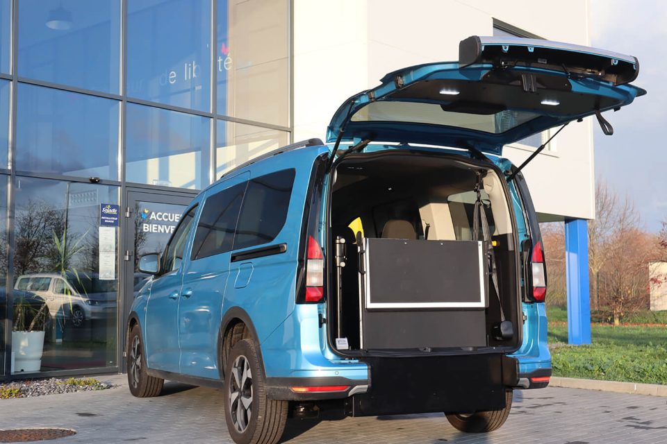 Ford Grand Tourneo Connect TPMR avec le hayon ouvert et sa rampe manuelle relevée à la verticale - véhicule handicap