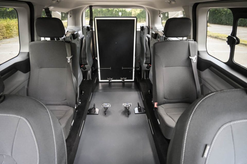 Ford Tourneo Custom TPMR vu de l'intérieur avec sa rampe relevée et ses sièges sur paroi en rang 3 et 4 repliés - véhicule TPMR - transport handicap