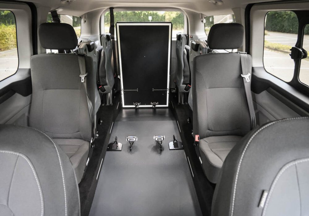 Ford Tourneo Custom TPMR vu de l'intérieur avec sa rampe relevée et ses sièges sur paroi en rang 3 et 4 repliés - véhicule TPMR - transport handicap