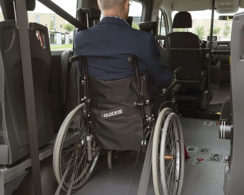 Personne handicapé dont le fauteuil roulant est fixé au plancher TriflexAir via son système d'ancrage