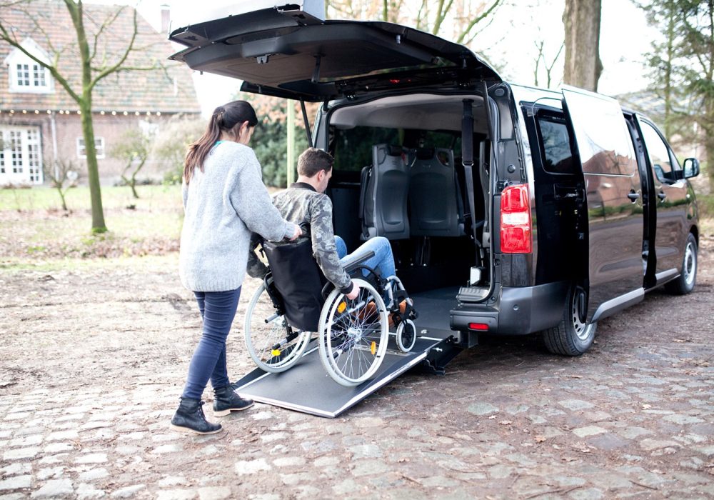 Citroën Spacetourer XL TPMR Noir Perla Nera vue depuis l'arrière avec le hayon ouvert, rampe déployée avec une personne en fauteuil montant de le véhicule - Véhicule TPMR - Voiture Handicap